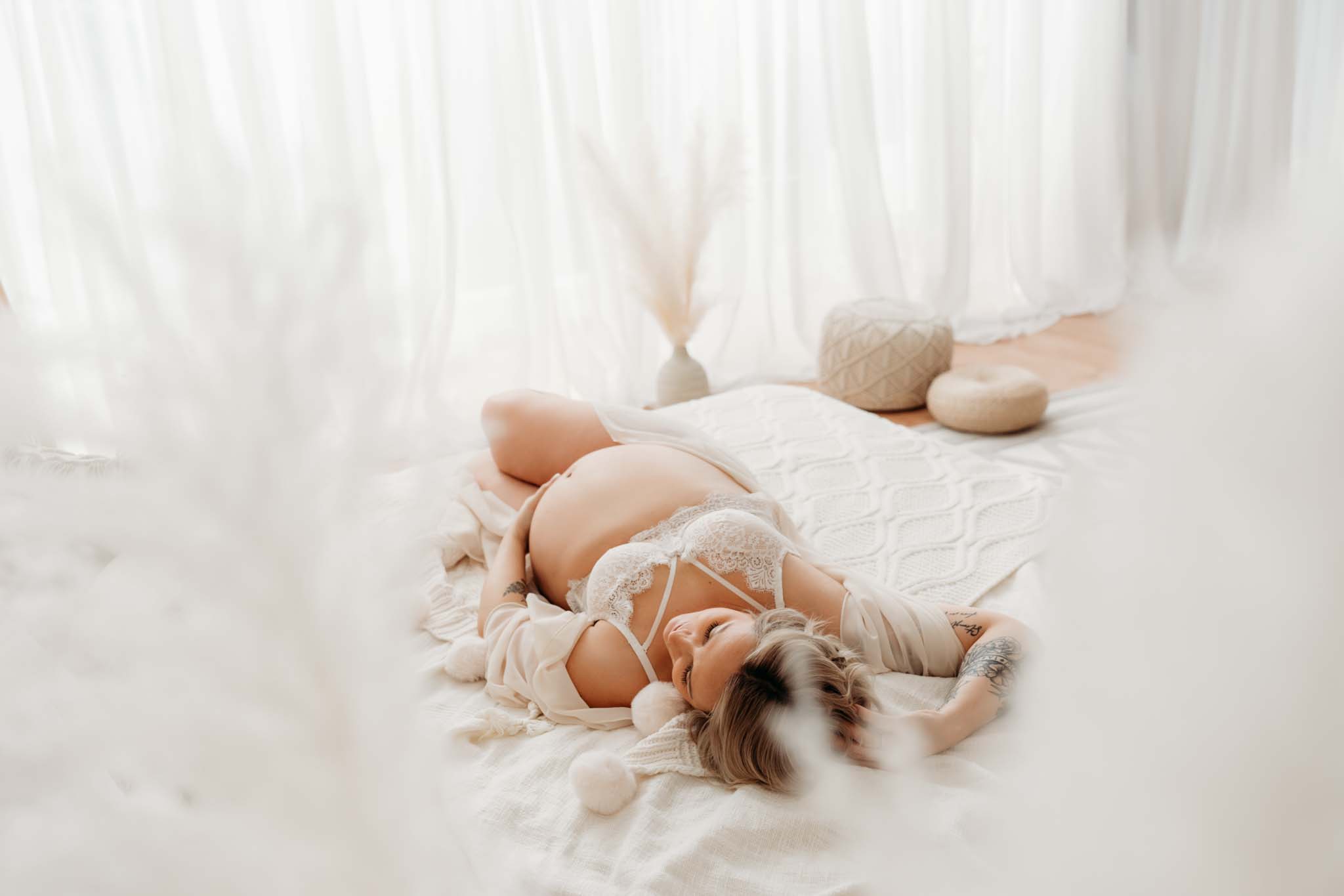 Schwangere Frau räkelt sich am Bett beim Babybauchshooting