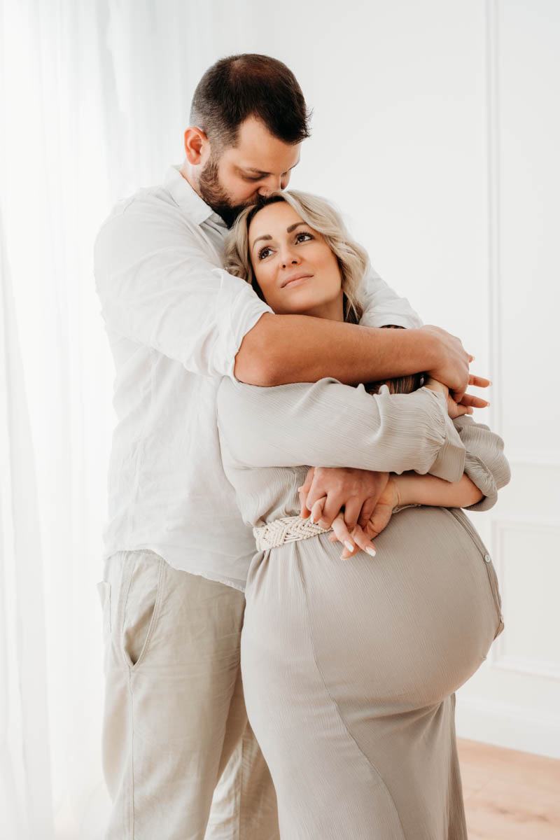 Mann umarmt schwangere Frau und hält sie ganz fest