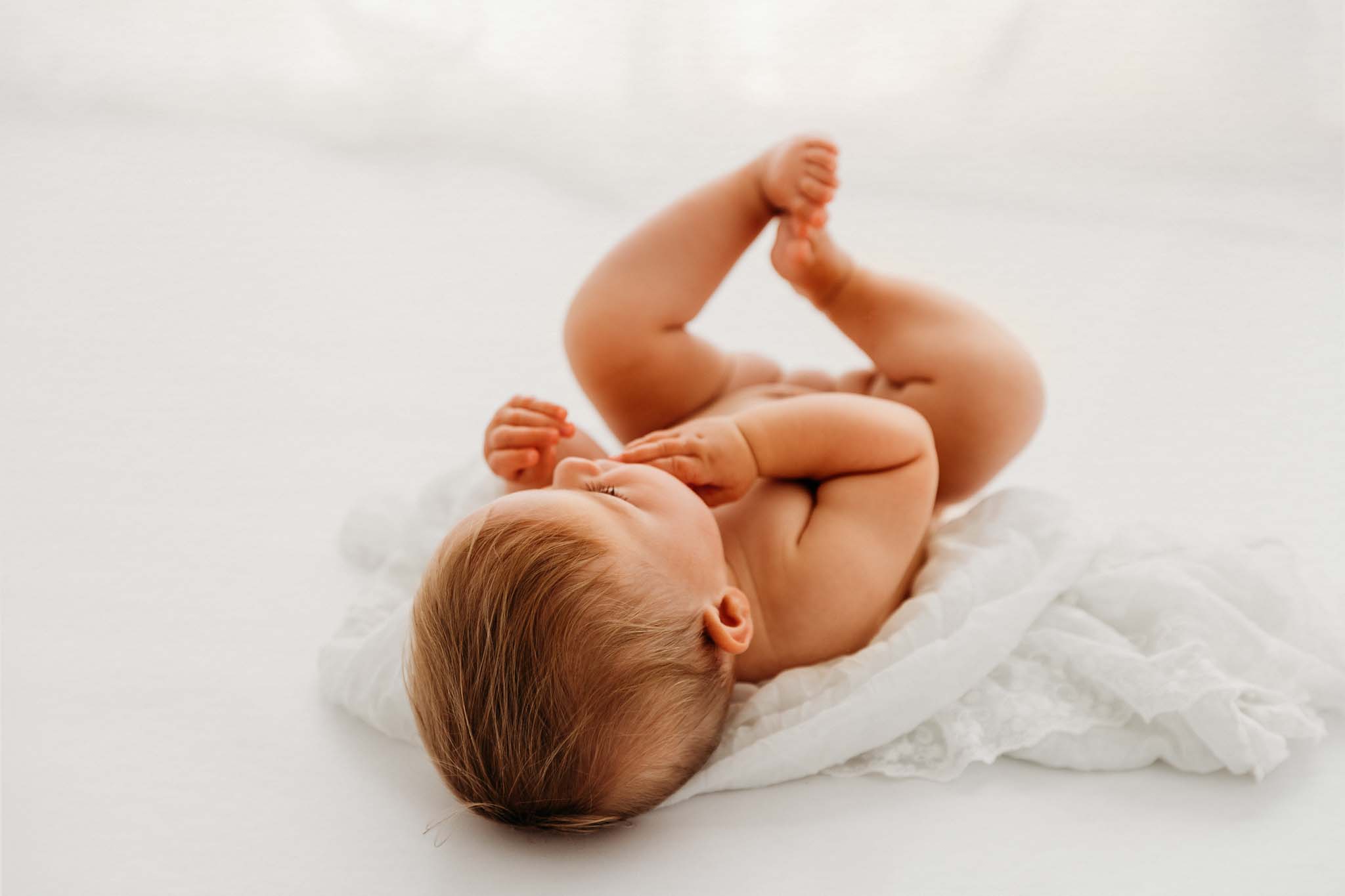 Baby liegt am Rücken in der Babyfotografie Babyfotografie Perspektive liegend