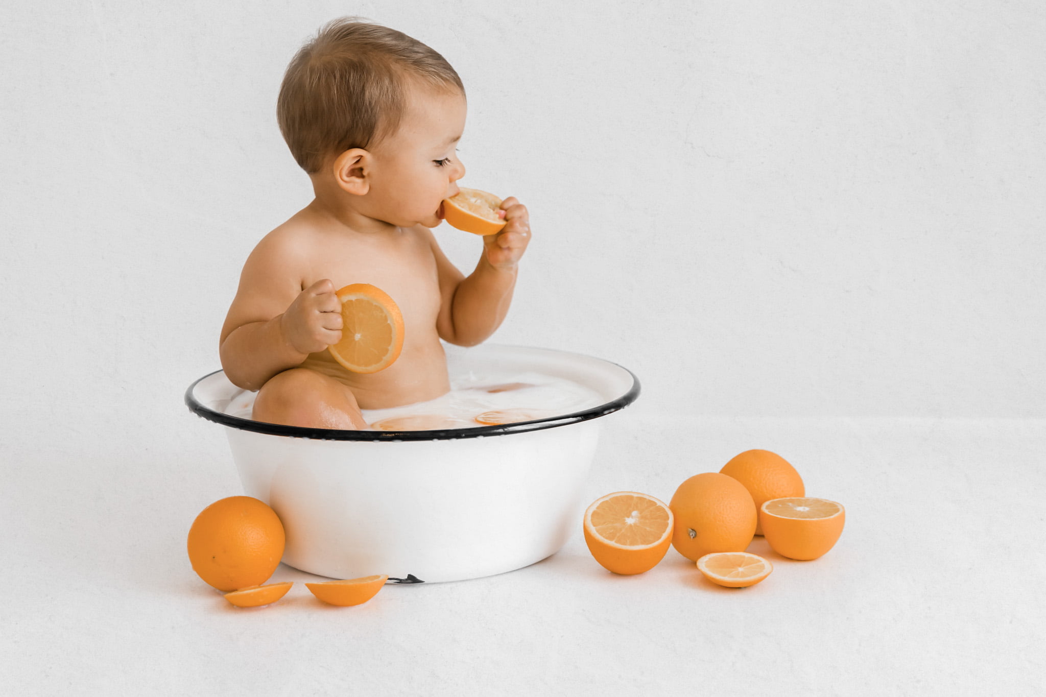 Baby beißt in Orange beim Baby Fotoshooting