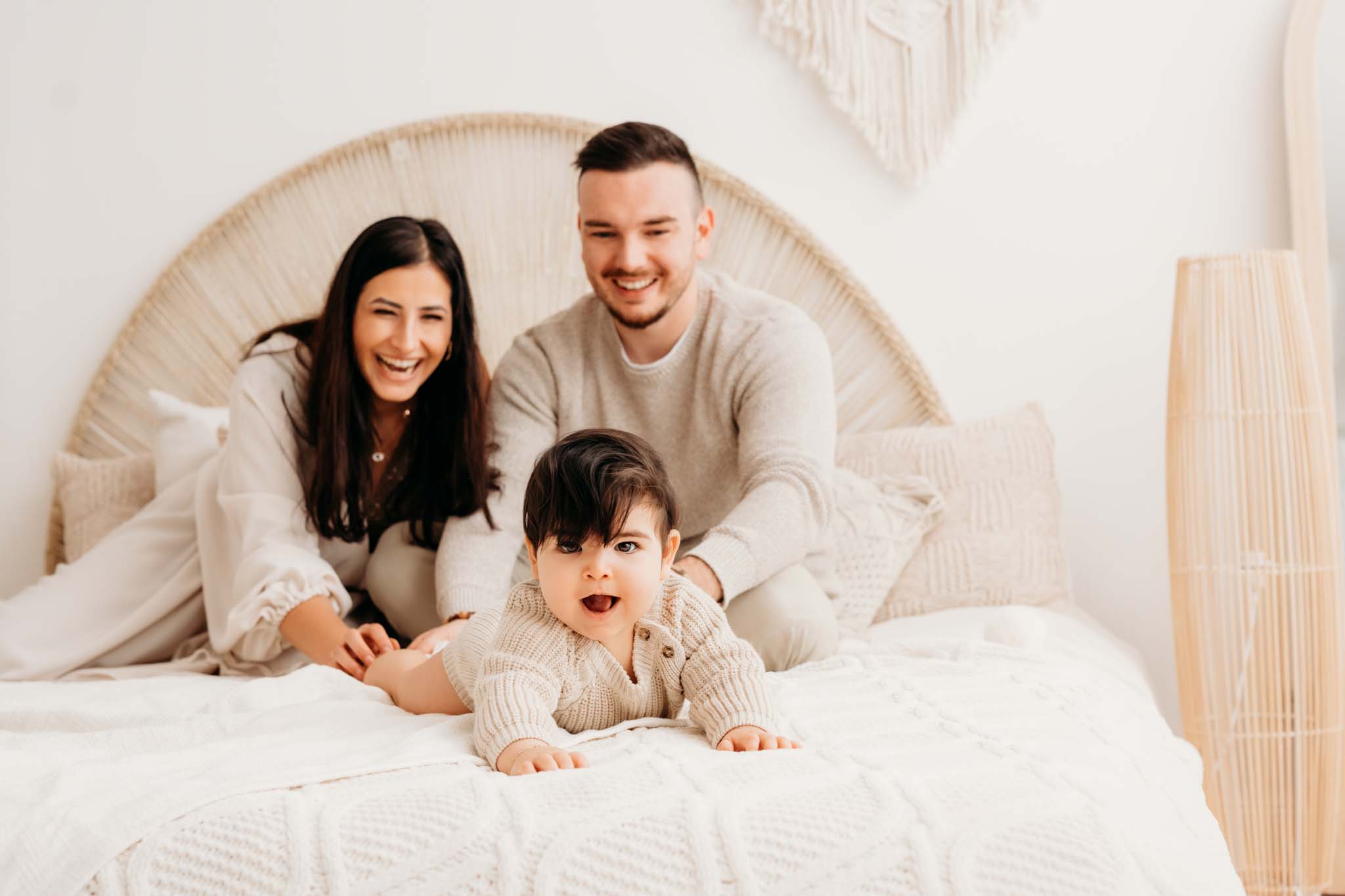 Baby krabbelt lachend Eltern am Bett davon beim Fotoshooting