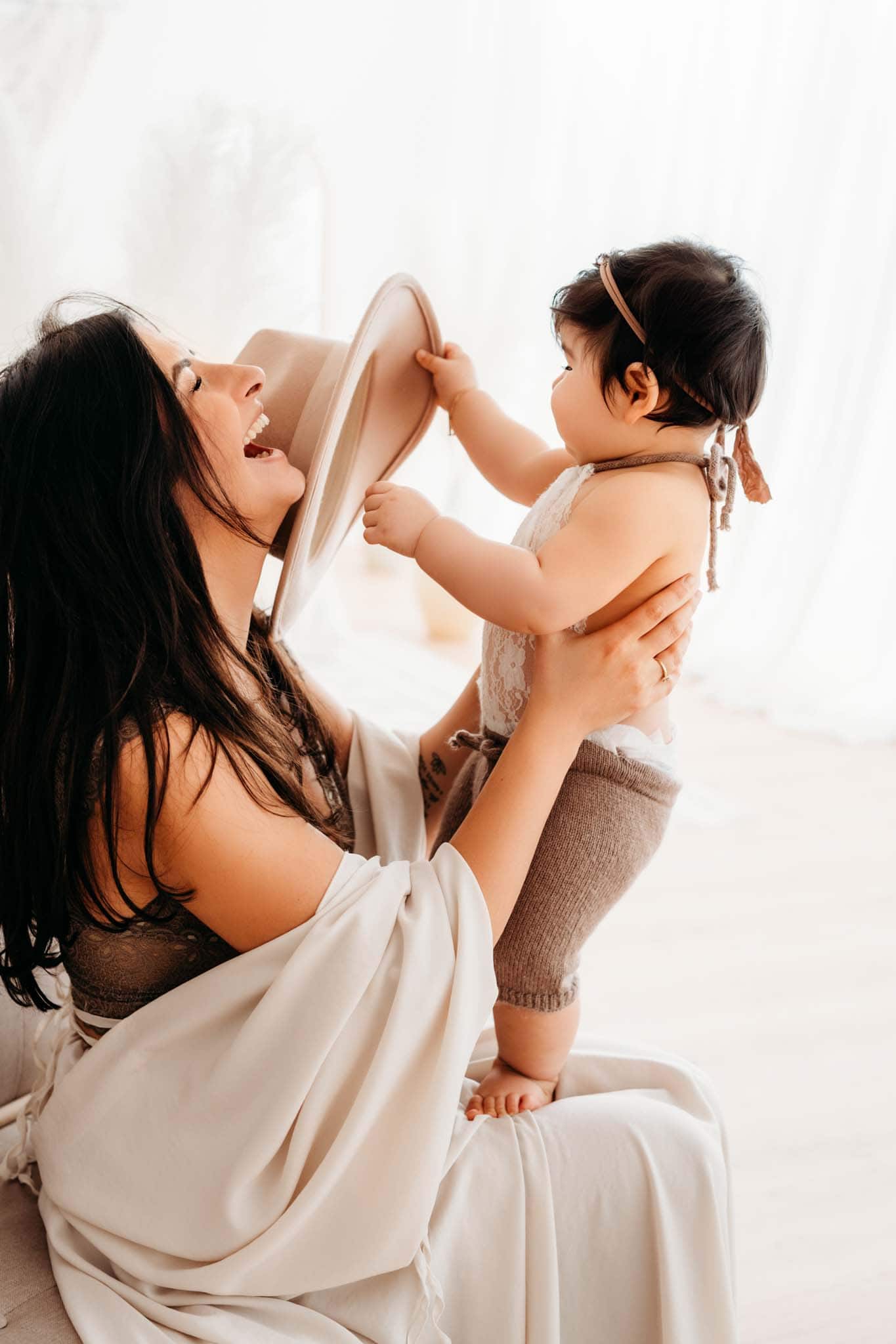 Baby klaut lachender Mama Hut vom Kopf