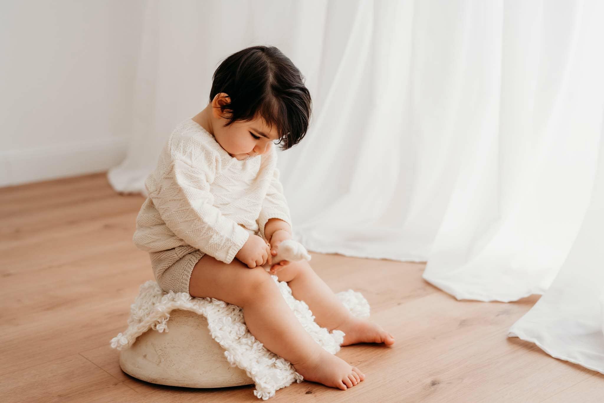 Baby sitzt hochkonzentriert auf Schale beim Fotoshooting München Baby sitzt hochkonzentriert auf Schale