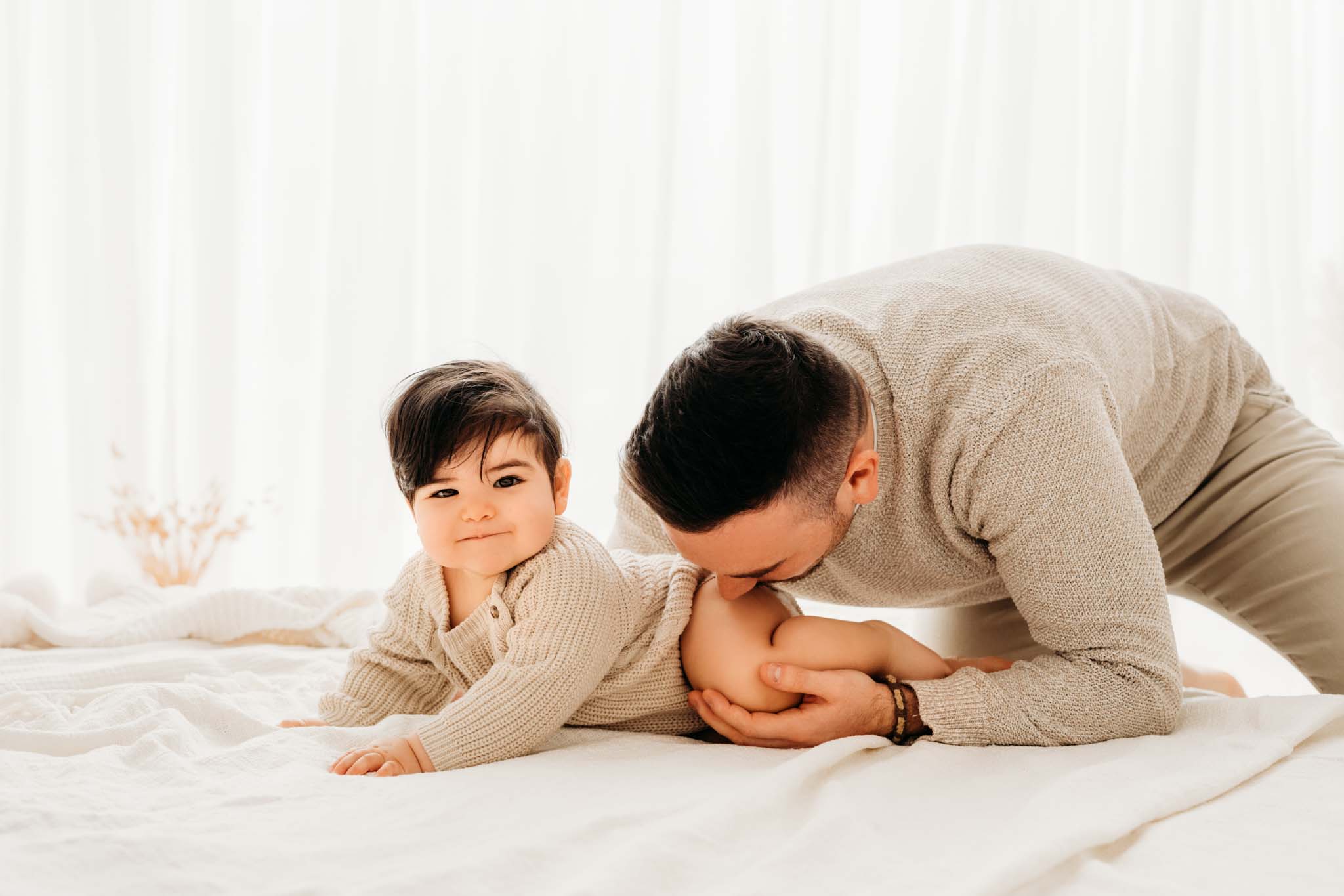 Papa beißt Kind beim Babyshooting München spielerisch in Popo Papa beißt Baby spielerisch in Popo
