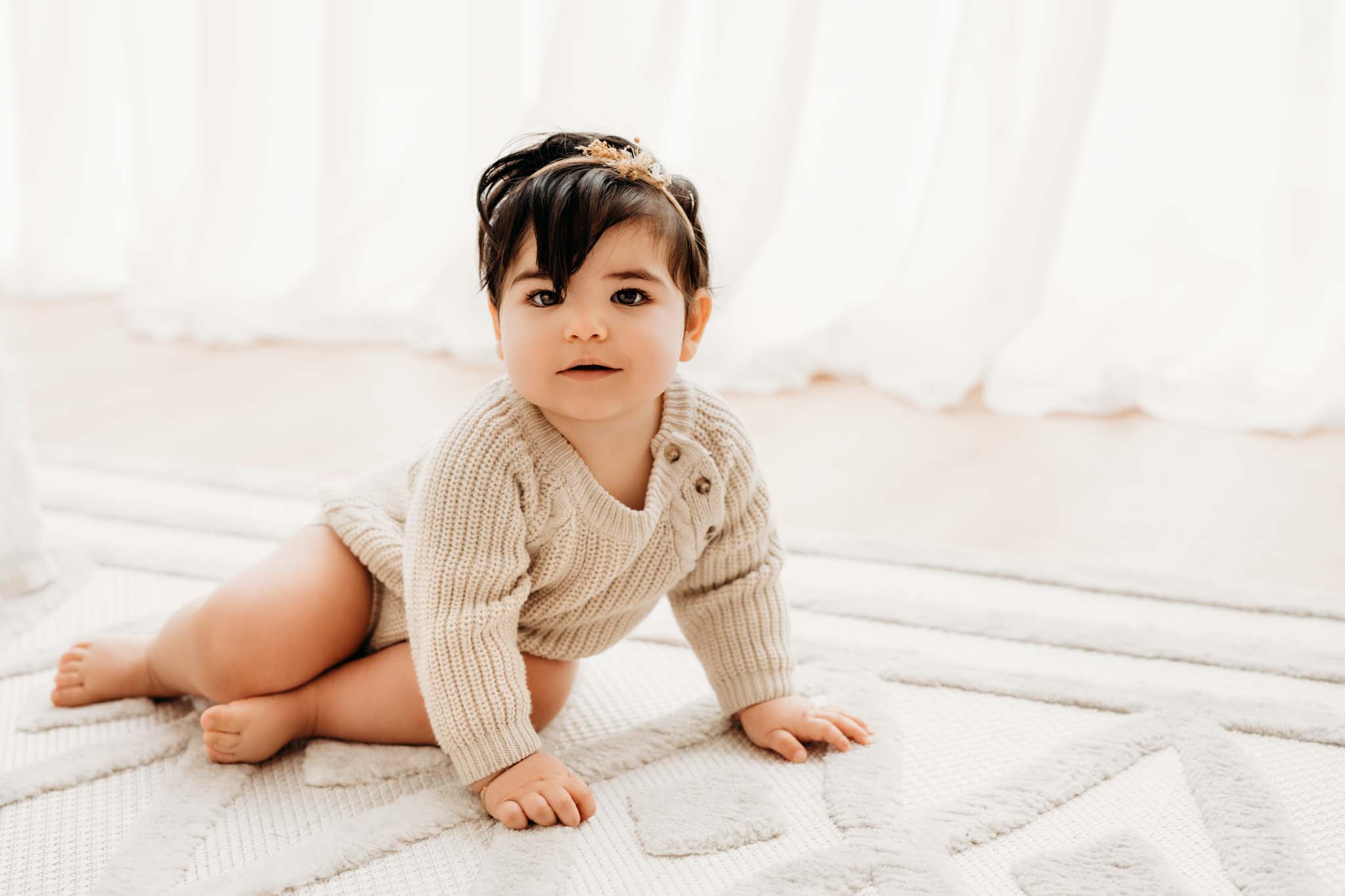 Sitzendes Baby beim Fotoshooting Baby sitzt am Teppich