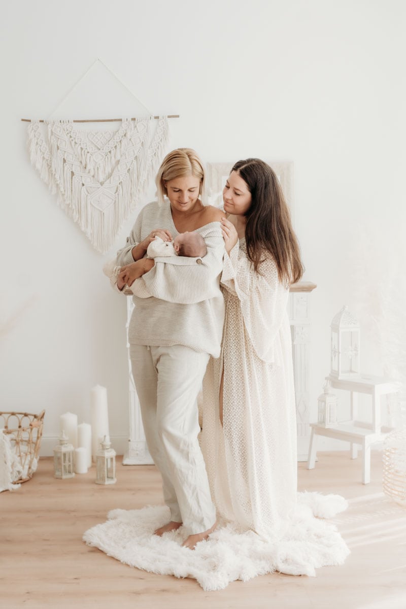 Zwei stolze Mamas mit ihrem neugeborenen Baby im Arm.