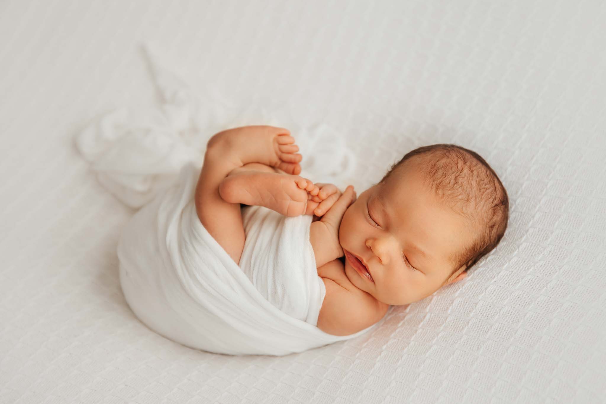 Neugeborenen-Shooting München Säugling auf weißer Decke beim Newborn-Shooting @Kathrin Schierl Fotografie