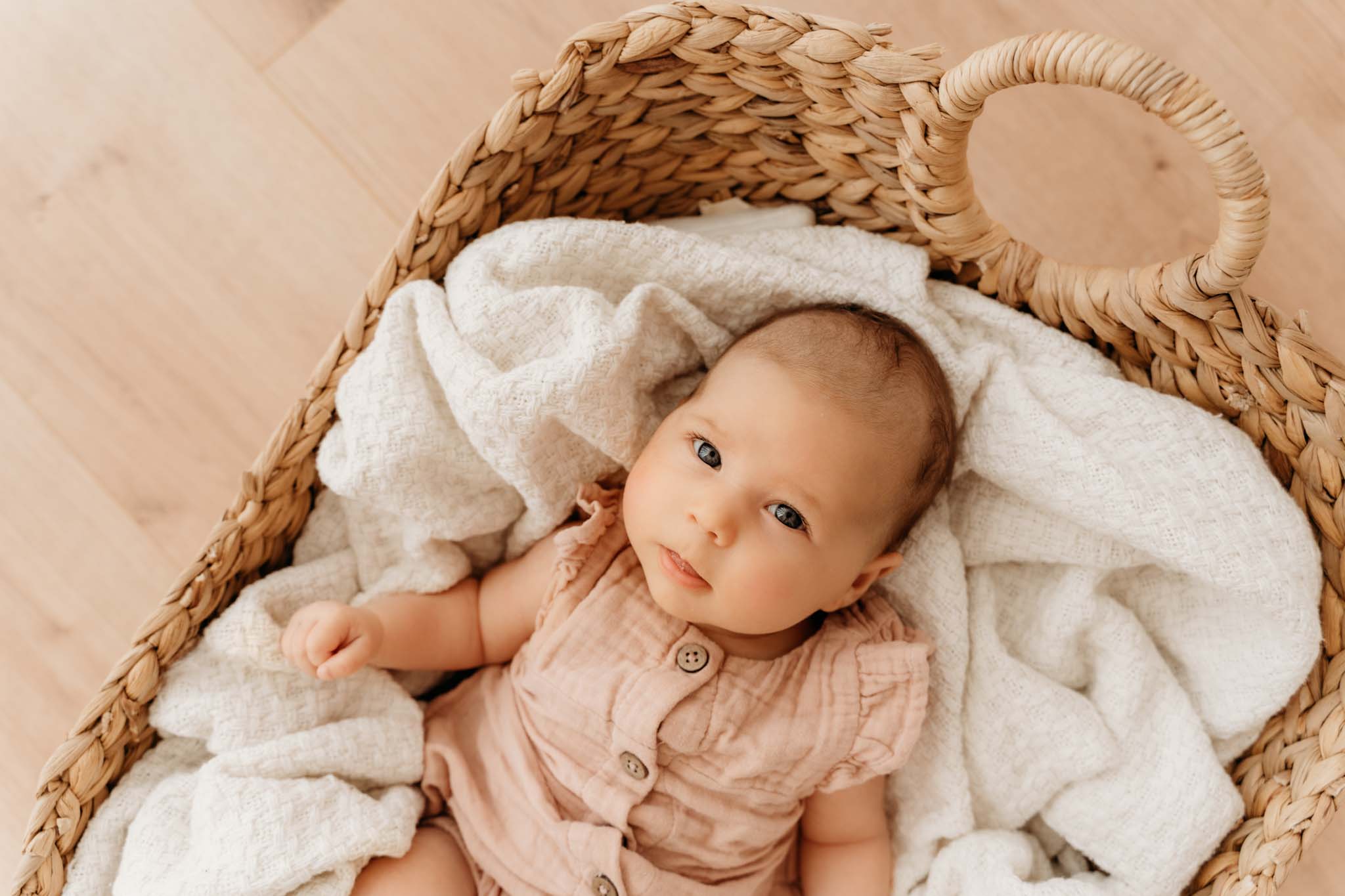 Neugeborenen-Shooting München Baby mit großen Augen und runden Backen im Korb