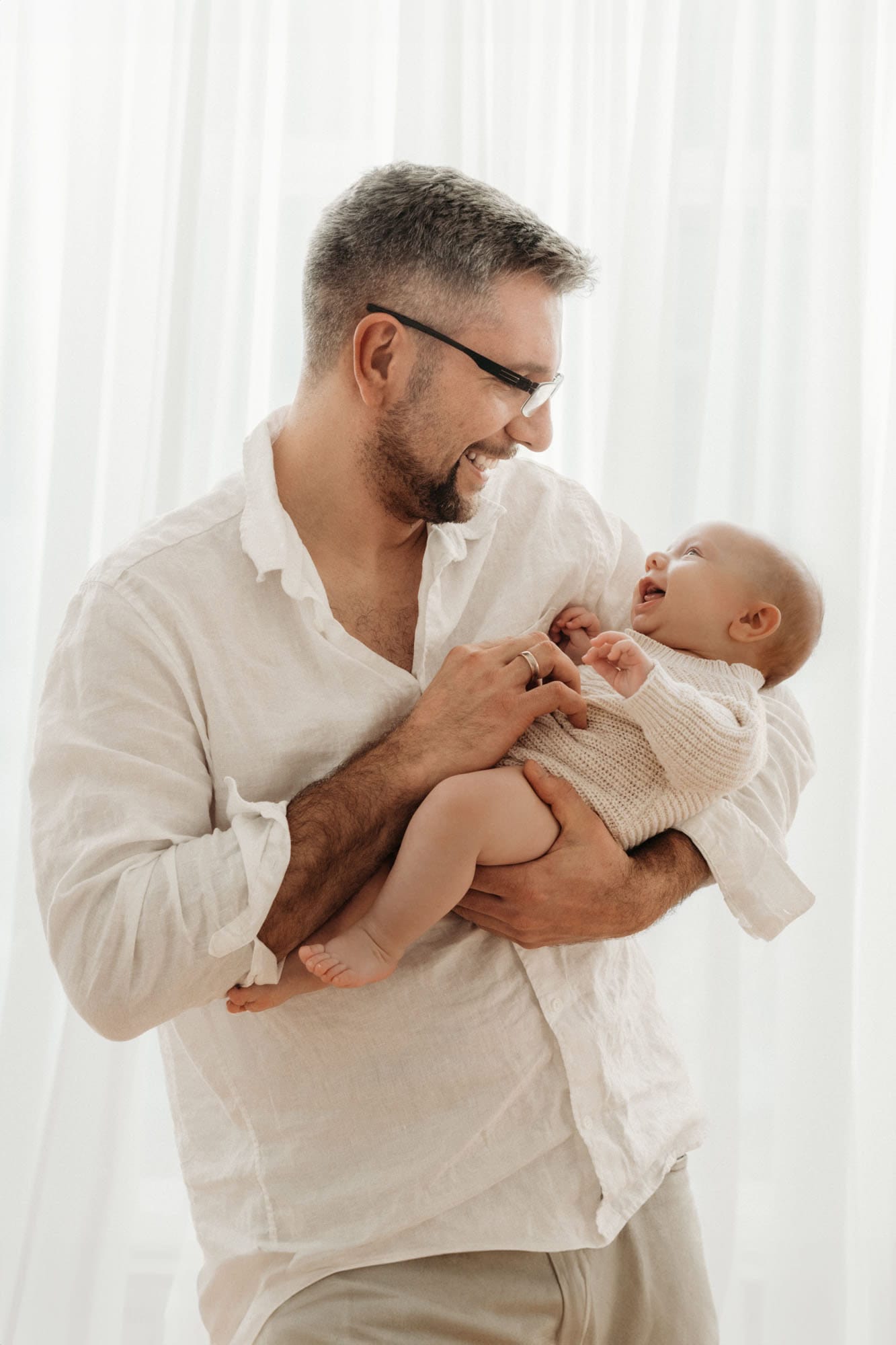 Papa spielt mit lachendem Baby beim Newbornshooting