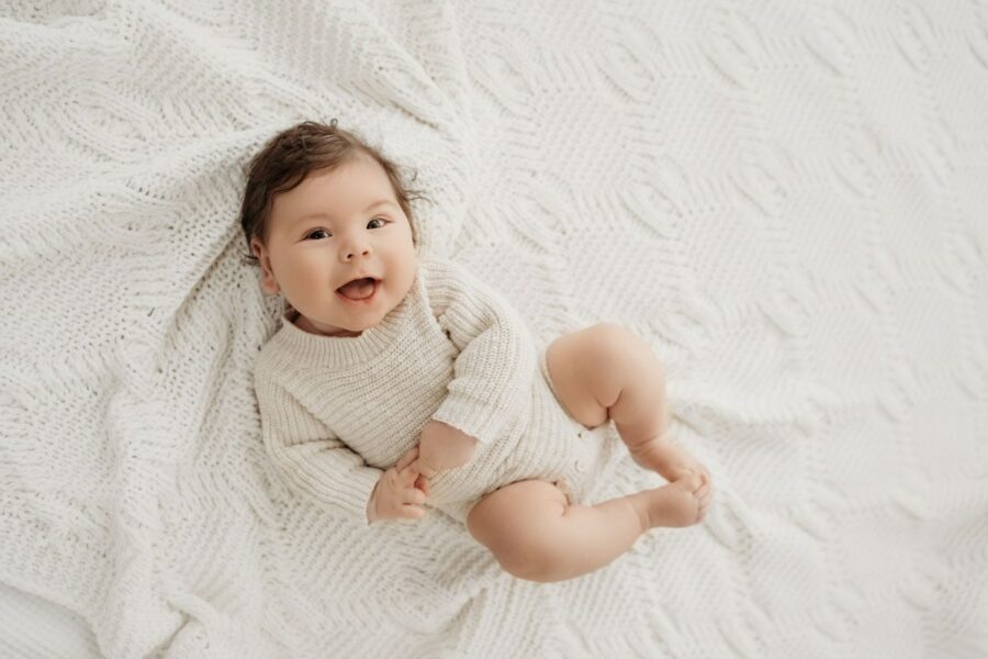 Neugeborenen-Shooting-Graz mit lachendem Baby auf Decke