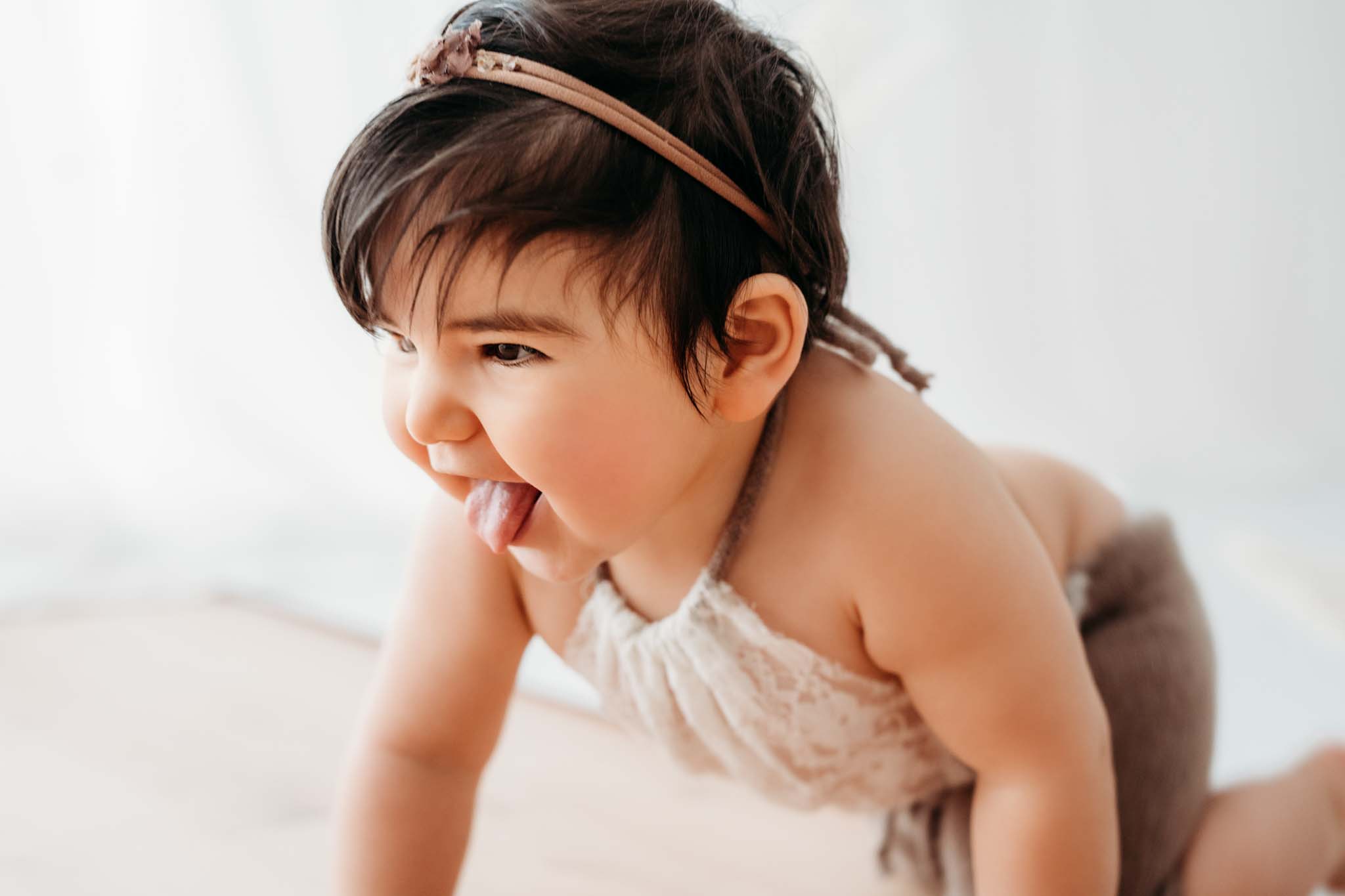 Baby streckt beim Babyfotoshooting Zunge beim Krabbeln raus Baby streckt Zunge raus beim Krabbeln