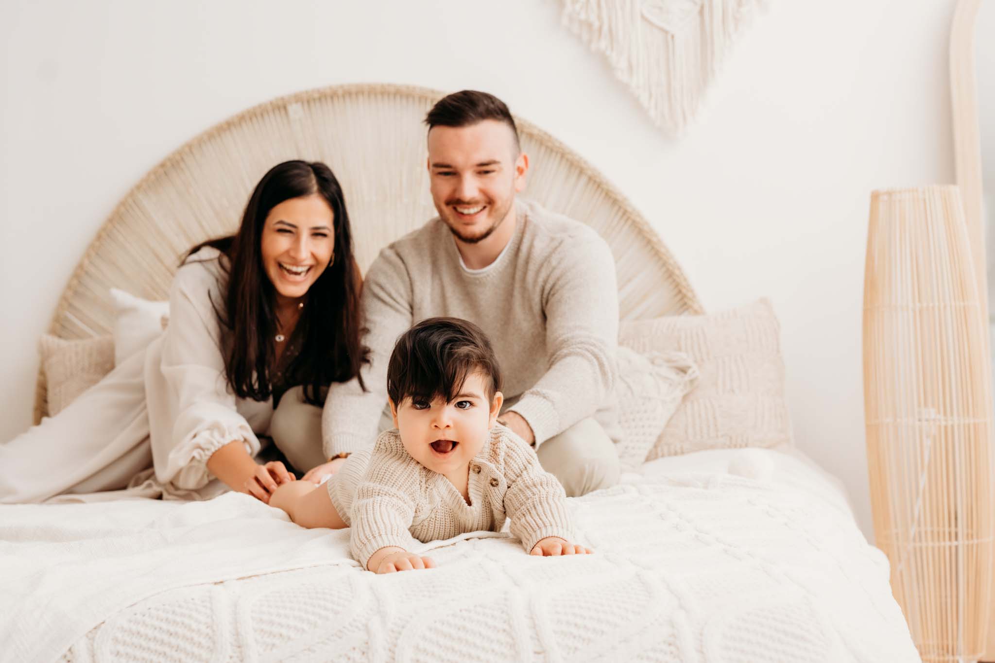 Familienshooting Graz mit krabbelnden Baby Baby krabbelt lachend Eltern am Bett davon beim Fotoshooting