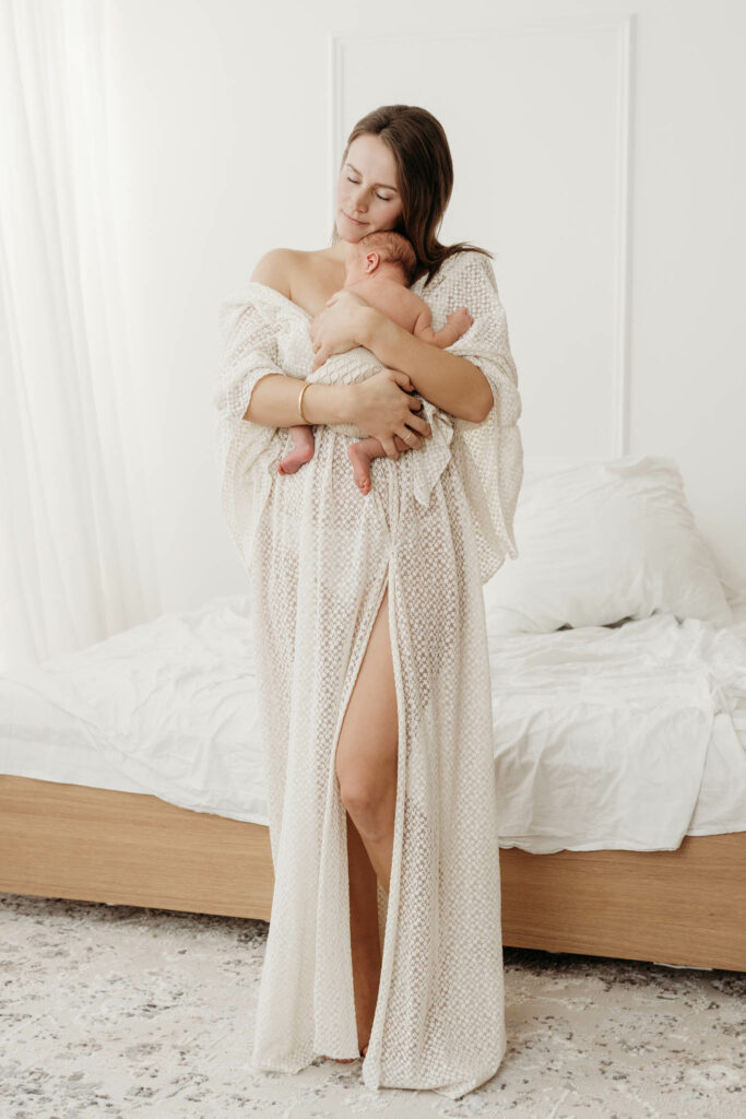 Mama in langem Kleid kuschelt mit ihrem Neugeborenen