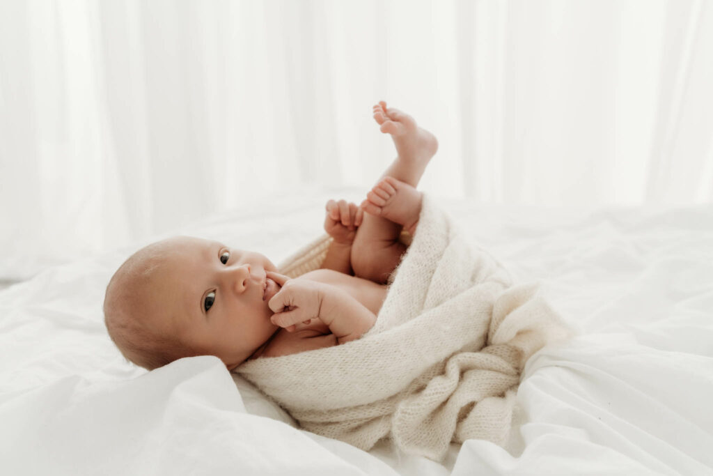 Newborn Baby in Tücher gewickelt schneidet Grimassen