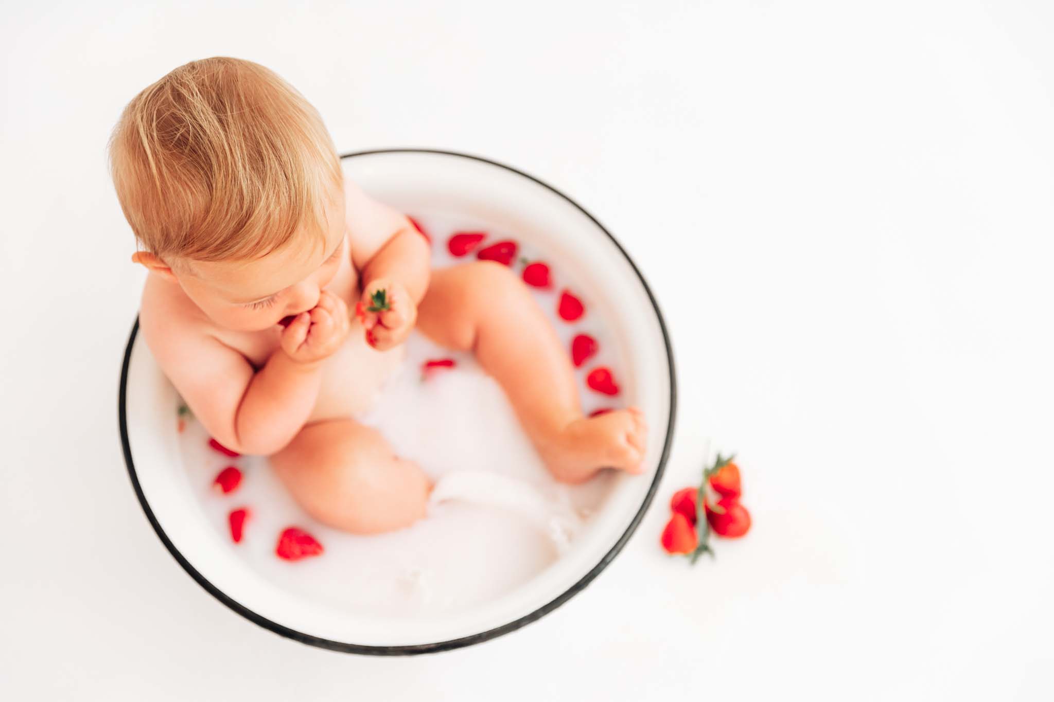 Baby in Milchbadewanne nascht Erdbeeren