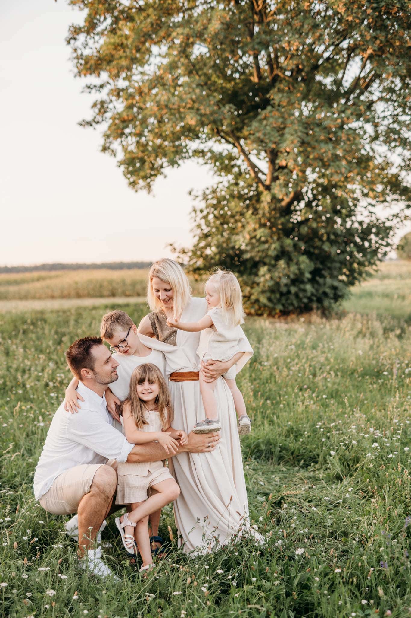 Familie umarmt sich auf einer Wiese bei Sonnenuntergang