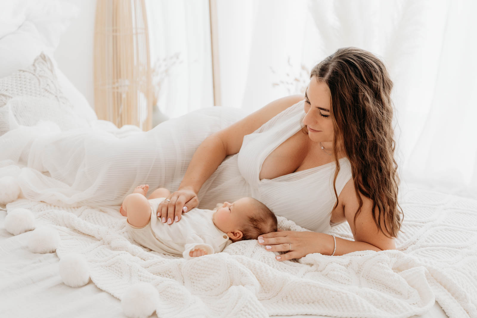 Babyzeit mit Mama kuschelnd am Bett Mama kuschelt mit Neugeborenen Baby - Genusszeit pur