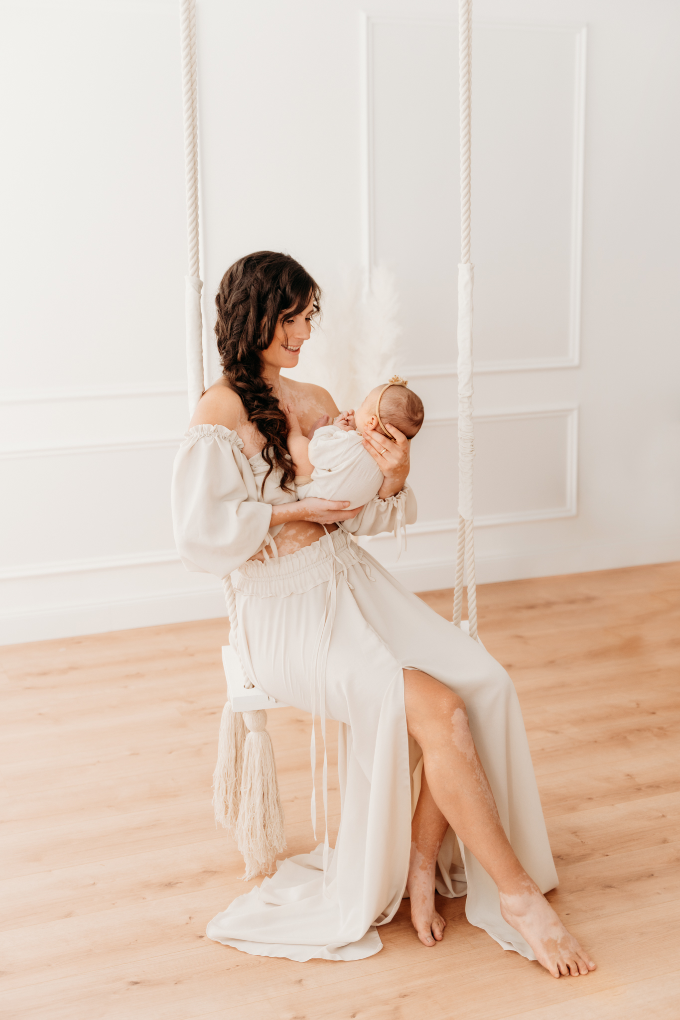 Mama sitzt mit Baby auf Vintage Schaukel beim Babyshooting Graz