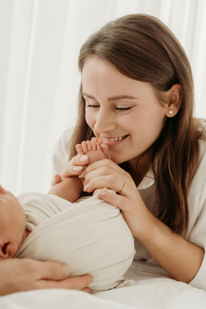 Mama küsst lachend Babys Zehen