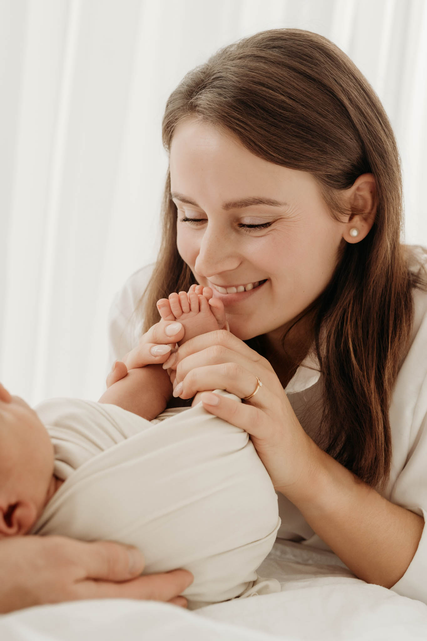 Mama küsst lachend Babys Zehen