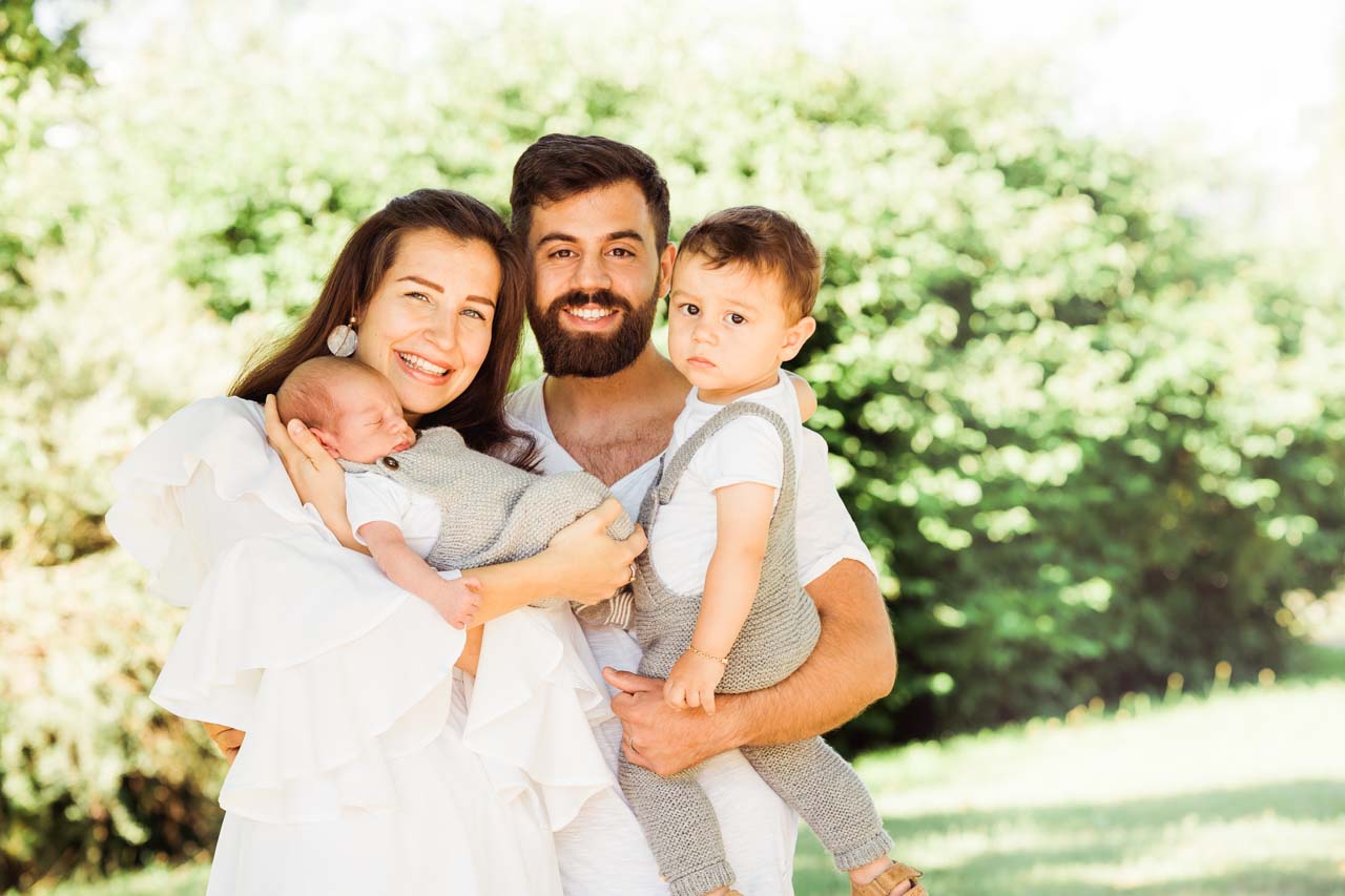 Familienfoto mit Baby beim Neugeborenenshooting outdoor im Grünen Familienfoto mit Baby und Geschwisterkind beim Neugeborenen-Shooting in der Natur